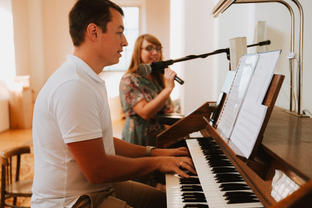 Emilia i Łukasz podczas oprawy muzycznej ślubu — śpiew i gra na instrumencie klawiszowym